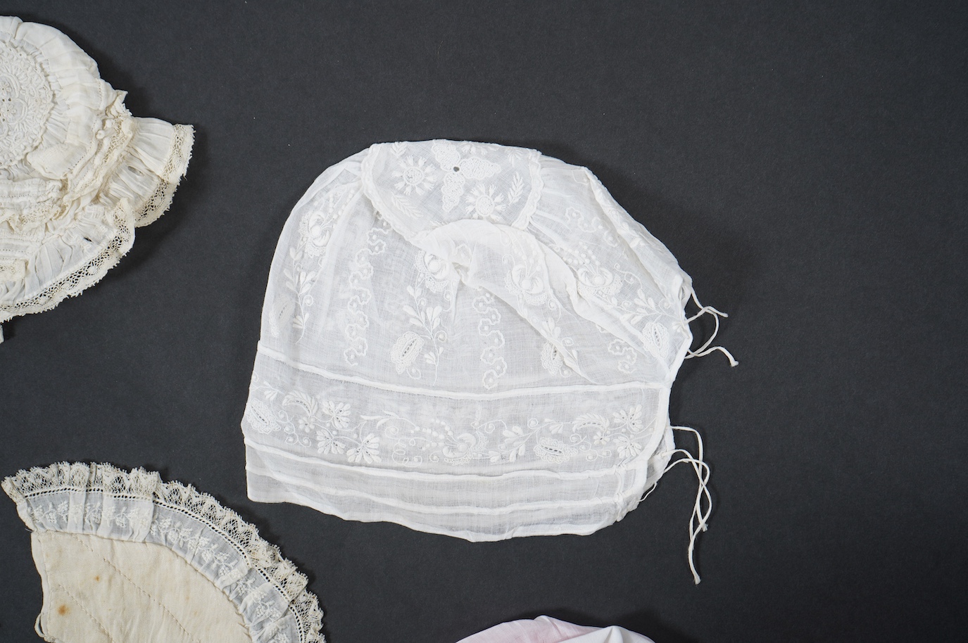 An 18th century Holly Point needle lace panelled linen baby bonnet, an early 19th century white worked baby bib and bonnet and a later 19th century finely ruffed lace bonnet (4). Condition - Holly Point bonnet and bib ha